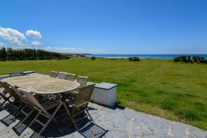 Large grassed garden and patio with outdoor seating area at Booby's Bay Cottage