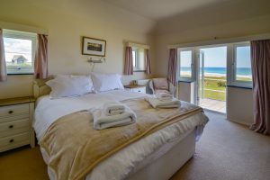 King sized bedroom with door to roof terrace and sea views at Booby's Bay Cottage