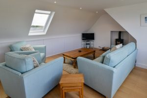 First floor lounge with seating, TV and log burner at Beachcombers
