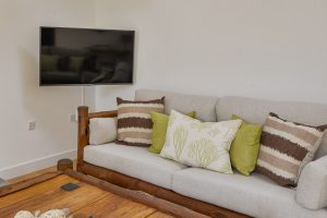 Sofa in lounge with decorative cushions and TV at Beachcombers