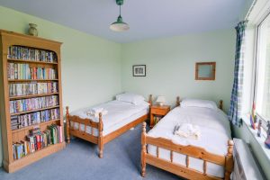 Twin bedroom with large bookcase at Bosporthennis