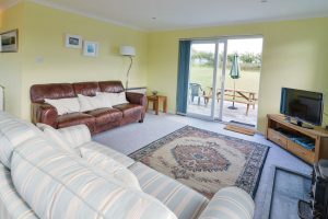 Seating in lounge at Bosporthennis with patio doors and TV