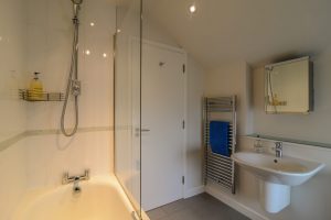 Bathroom with bath and overhead shower at Cheyney