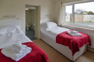 Twin ensuite bedroom at Cobs with doors leading to ensuite and garden views