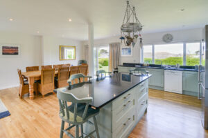 Open plan kitchen with island and bar stools, and separate dining area at Curlews