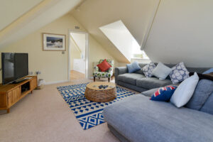 First floor lounge area with corner sofa and TV at Curlews