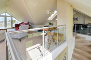 Stairs leading up to first floor lounge with glass balustrades at Curlews