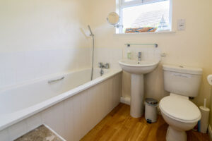 Bathroom with bath, overhead shower, loo and basin at Curlews