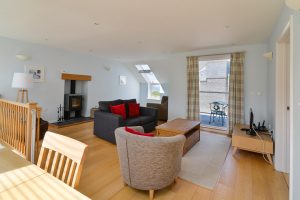 Lounge area with sofa bed, TV, log burner and balcony at Aquataine Annexe
