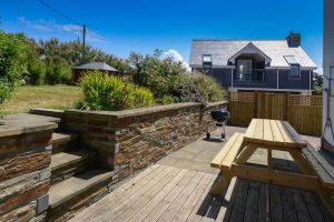 Rear garden decking with bench and BBQ with steps up to grassed area at Aquataine Lodge