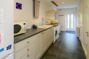 Large utility room at Blue Seas with external door, washing machine and dryer
