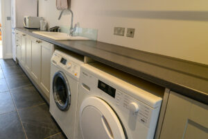 Utility room with washing machine and tumble dryer at Blue Seas