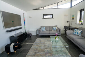 Spacious sitting room at Morvoren with mounted TV and desk area