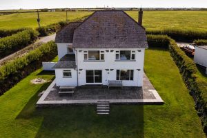 Exterior aerial view of the beach side of the house with patio and grassed lawn around South Corner