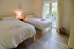 Twin bedroom with double patio doors leading to garden at Gortheren