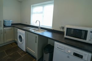 Utility room at Herongate with sink, microwave, washing machine and dryer