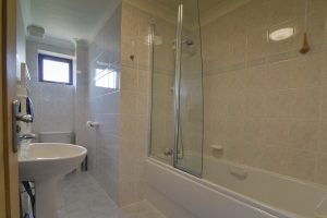 Main bathroom on the first floor at High Tides with toilet, wash basin and bath with shower over
