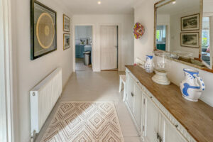 Hallway with wooden painted floor and rug from front entrance door with doors into kitchen and bathroom 3 at Penamont