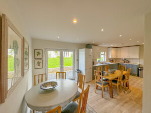 Open plan dining and kitchen areas at Penamont showing two table with ample chairs and double doors out to the rear patio and garden
