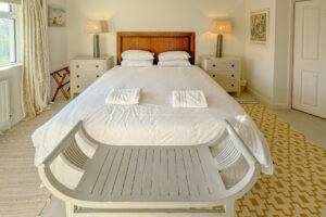 Superking bed in ensuite bedroom 1 at Penamont with bedside tables, lamps and rungs on painted wooded floor