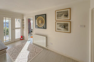 Entrance hallway at Penamont with wall art and rug on painted wooden floor with doorway into the lounge