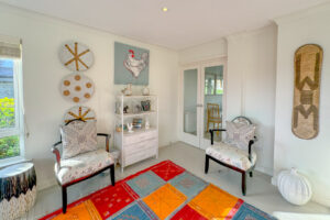 Corner of the lounge with occasional chairs, unit with ornaments, wall art and double glazed doors into the dining area