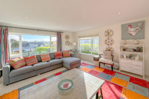 Lounge at Penamont with large windows to the front and side of the house, wall art and ornament on unit