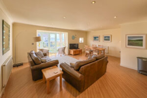 Open plan lounge/dining area with sea view through double doors at Apartment 5 Greenwaves