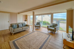 Ground floor lounge area with TV and sea views at Aquataine Lodge