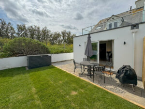 Rear grassed garden and patio are with furniture at Penjerrick