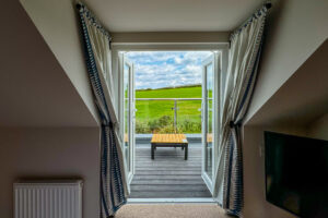 Double doors onto balcony from the twin room at Penjerrick with views across field