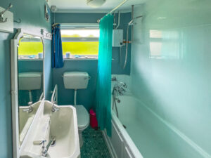 Bathroom at Thalassa with bath and shower over, toilet and wash hand basin