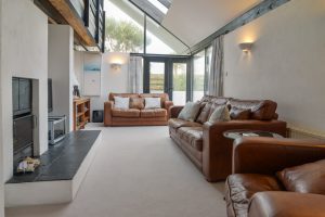 Living room at Morvoren with ample seating, TV and log burner