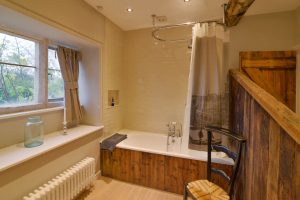 Bathroom with bath tub and overhead shower at Pensile House Cottage