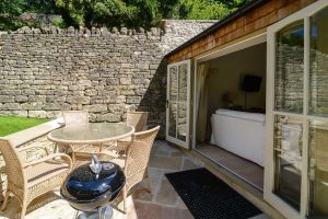 Rear exterior of Pensile House Cottage with seating and a BBQ