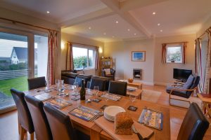 Open plan dining and lounge areas at Parc Vean with dining table and chairs and seating and TV in lounge area.