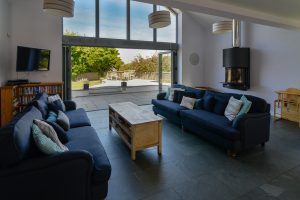 Lounge at Ridgegrove with mounted log burner and TV with bifold doors