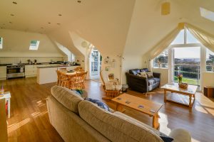 Open plan living area with doors from dining and lounge areas onto balcony at Sailaway
