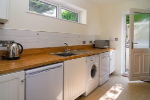 Lower garden level utility area at Sailaway with laundry facilities, microwave, kettle and door to outside