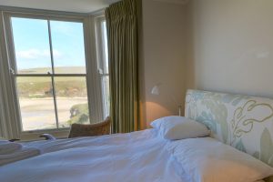 Superking bed and seating in first floor master bedroom with bay window with view of beach at Santa Marina