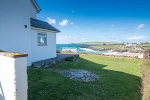 View from the side of South Corner over grassed lawn and beach towards Trevose Head