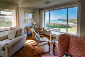 Lounge area at South Corner with large window view over the grassed lawn and Treyarnon Bay