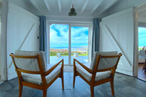 Area between the lounge and kitchen dining area at The Buck with chairs looking out over the garden through large glass doors