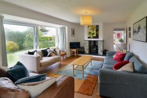 Lounge at The Ridings with sliding doors to the font patio seating tv and wood burner