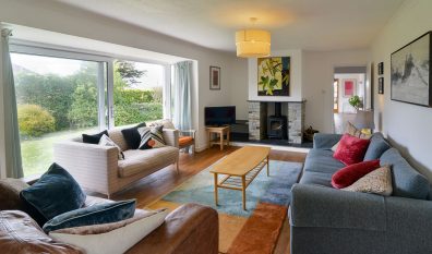 Lounge at The Ridings with sliding doors to the font patio seating tv and wood burner