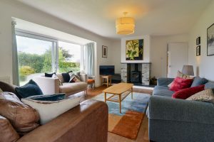 Lounge at The Ridings with sliding glass door onto the front patio ample seating and wood burner