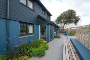 Exterior front entrance and paved area with flower bed and built in bench seating
