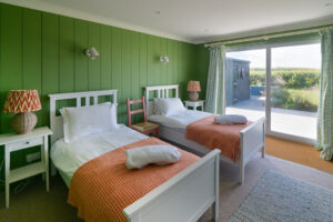 Ground floor twin bedroom at Torridon with large glass doors to the rear patio