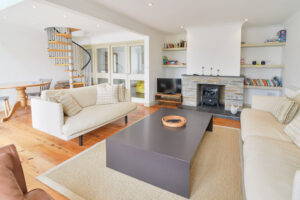 The lounge at Tregarne with comfortable seating dining table and chairs woodburner and TV