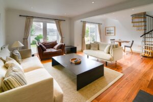 The lounge at Tregarne with spiral staircase to the mezzanine, doors to the rear patio and comfortable seating